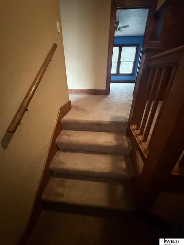 stairway with carpet floors, ceiling fan, and baseboards