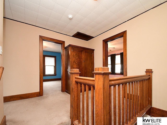 hall with carpet floors, an upstairs landing, and baseboards