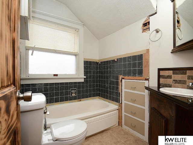 bathroom with a textured ceiling, tile patterned flooring, a washtub, toilet, and vaulted ceiling