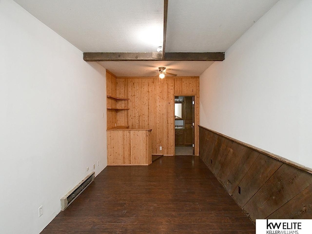 unfurnished room featuring a baseboard radiator, beam ceiling, a wainscoted wall, and wooden walls