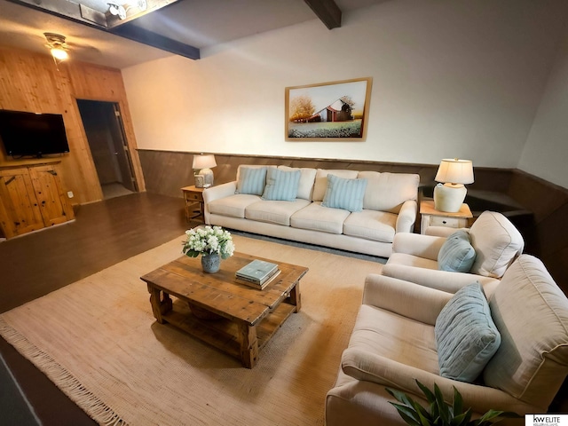 living room with beam ceiling, wainscoting, ceiling fan, wood walls, and wood finished floors