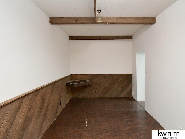 interior space with a wainscoted wall, wood walls, wood finished floors, and beam ceiling