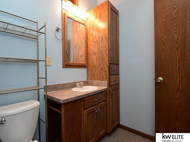 bathroom featuring toilet, baseboards, and vanity