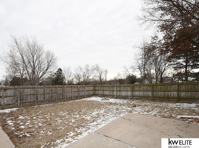 snowy yard with a fenced backyard and a patio