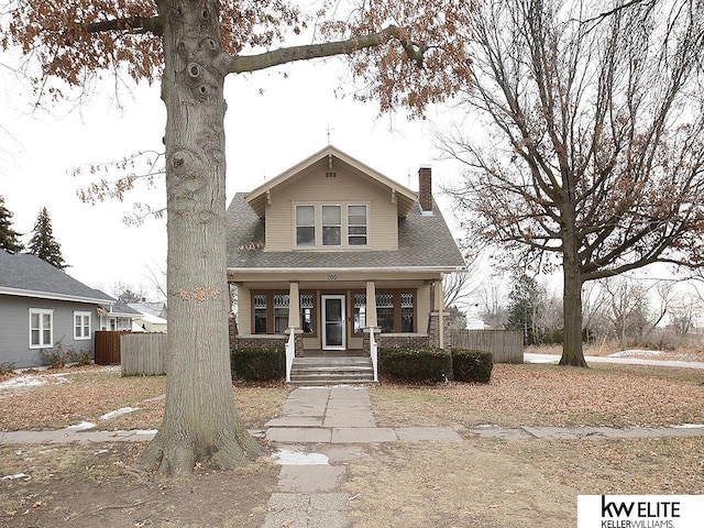 bungalow-style home featuring a porch, a chimney, and fence