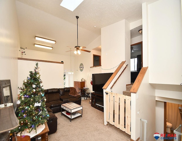 living room with a skylight, carpet flooring, ceiling fan, a textured ceiling, and stairs