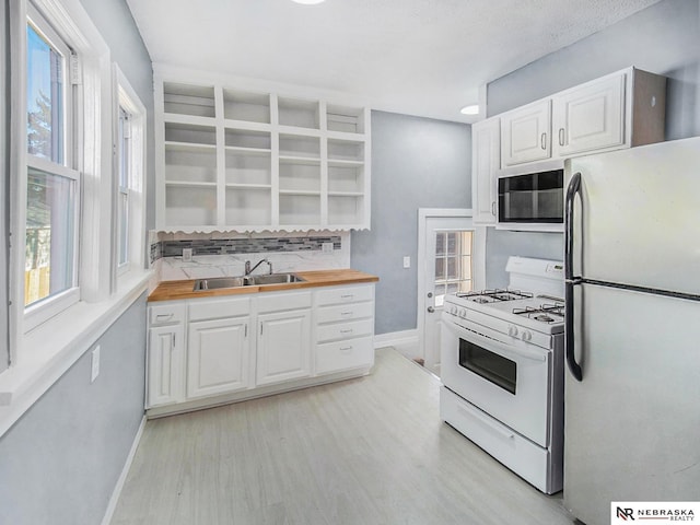 kitchen featuring open shelves, decorative backsplash, white cabinets, a sink, and white appliances