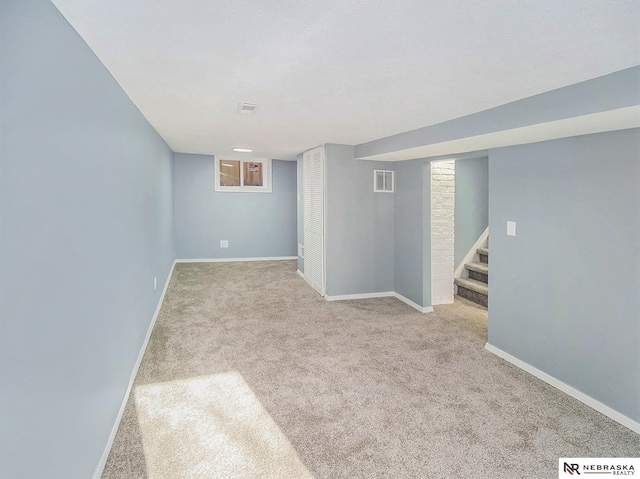 finished below grade area with carpet floors, visible vents, baseboards, and stairs