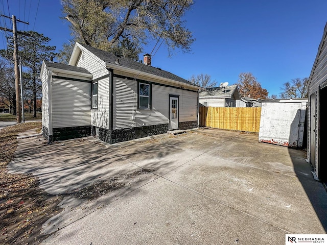 rear view of property with a chimney and fence