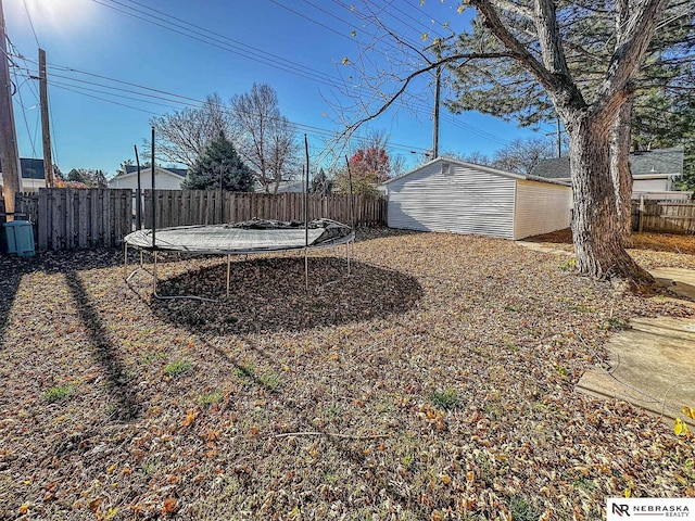 view of yard with a storage unit, a trampoline, an outdoor structure, and a fenced backyard