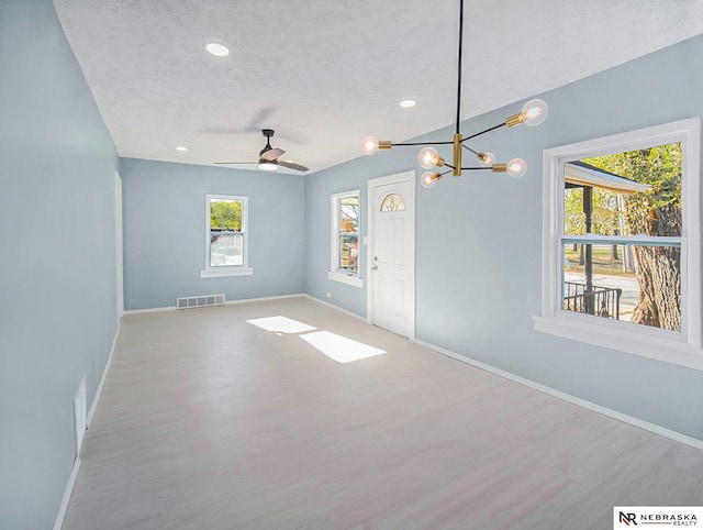 spare room featuring baseboards, visible vents, a textured ceiling, and wood finished floors