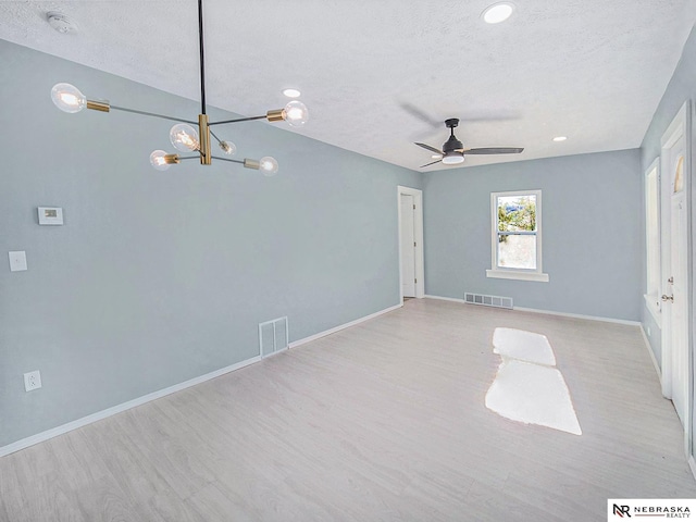 spare room featuring visible vents, a textured ceiling, baseboards, and wood finished floors