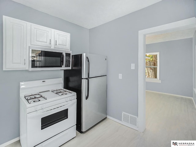 kitchen with appliances with stainless steel finishes, visible vents, baseboards, and white cabinetry