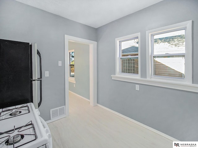 kitchen with freestanding refrigerator, white range with gas stovetop, visible vents, and plenty of natural light