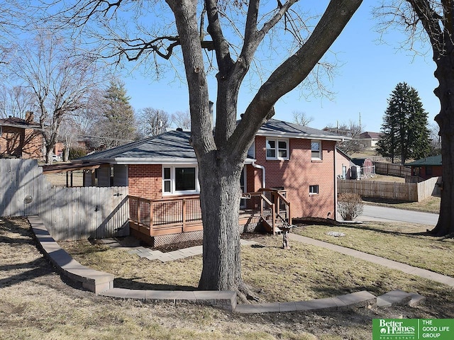 rear view of house with brick siding, a wooden deck, and fence