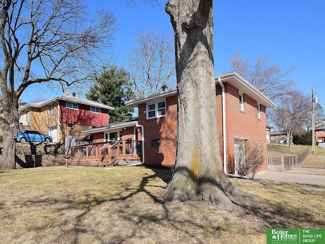 back of property featuring brick siding, a lawn, a chimney, and a deck