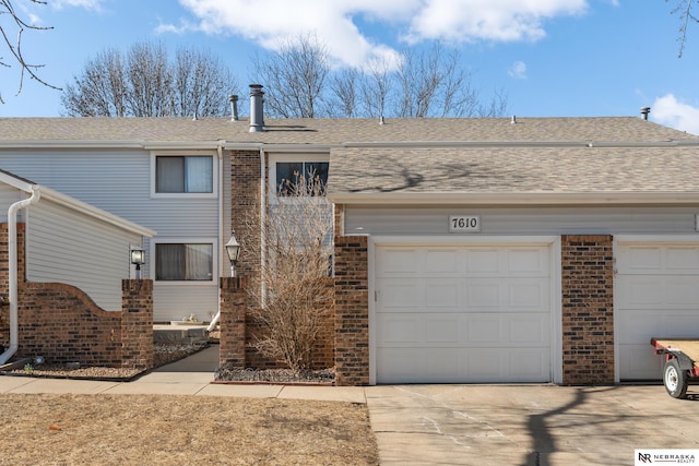 view of front of home with driveway, roof with shingles, and brick siding