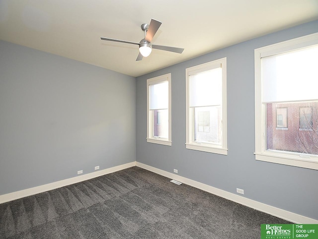 spare room featuring ceiling fan, baseboards, and dark colored carpet