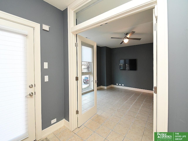 empty room featuring a ceiling fan, baseboards, and light tile patterned floors