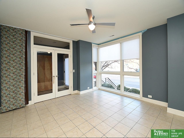 empty room with light tile patterned floors, french doors, baseboards, and floor to ceiling windows