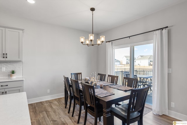 dining room with light wood-type flooring, baseboards, and a notable chandelier