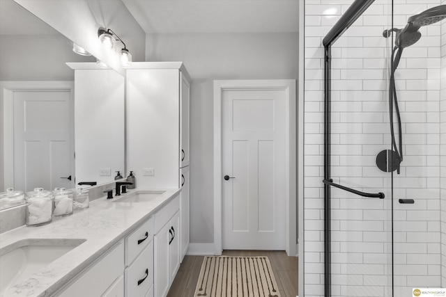 full bathroom featuring double vanity, a stall shower, and a sink