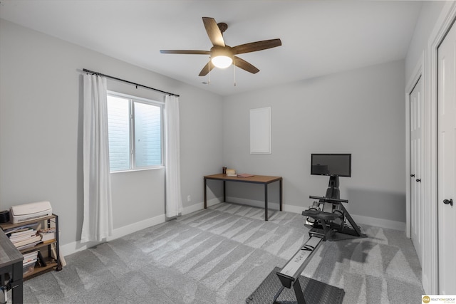 carpeted office space featuring ceiling fan and baseboards