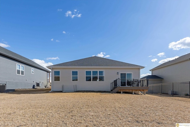 rear view of property featuring central AC, a yard, a wooden deck, and fence