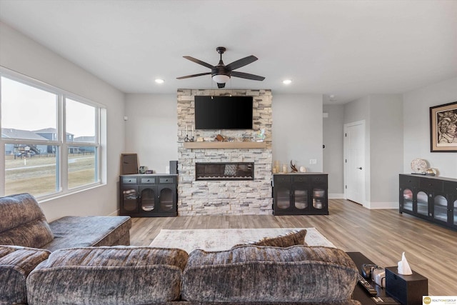 living room featuring ceiling fan, a stone fireplace, recessed lighting, wood finished floors, and baseboards