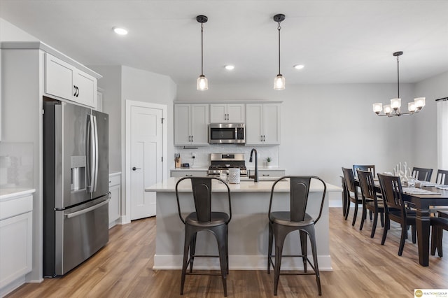 kitchen featuring stainless steel appliances, light wood-type flooring, light countertops, and tasteful backsplash