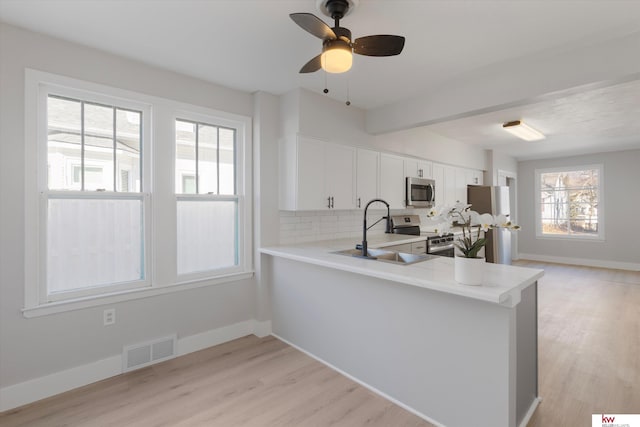 kitchen with a sink, visible vents, light countertops, appliances with stainless steel finishes, and tasteful backsplash