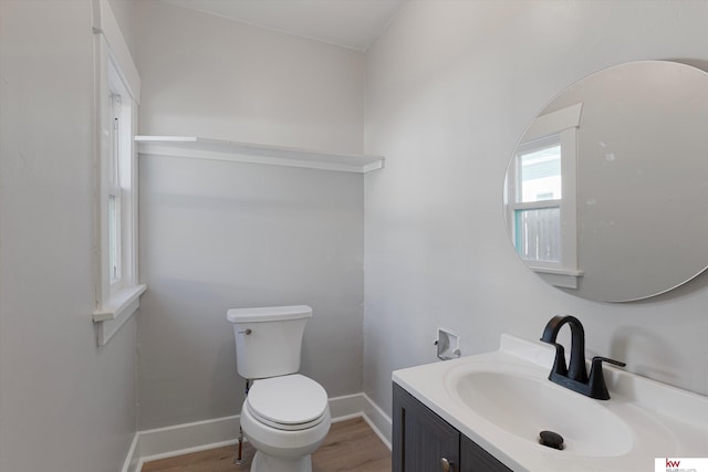 bathroom featuring toilet, vanity, baseboards, and wood finished floors