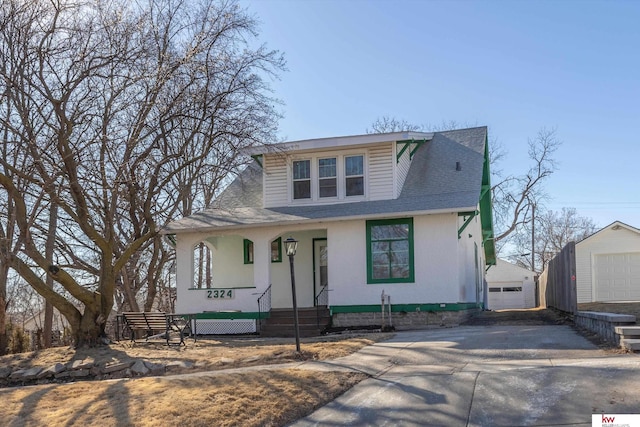 view of front of home featuring covered porch, a shingled roof, an outdoor structure, a detached garage, and concrete driveway