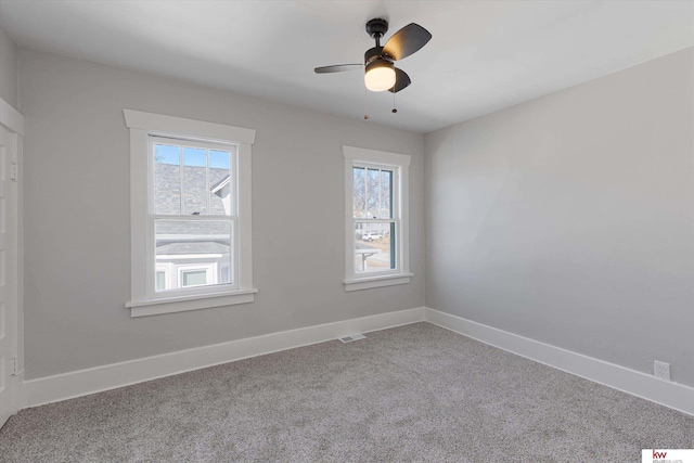 carpeted spare room with baseboards, a ceiling fan, visible vents, and a healthy amount of sunlight