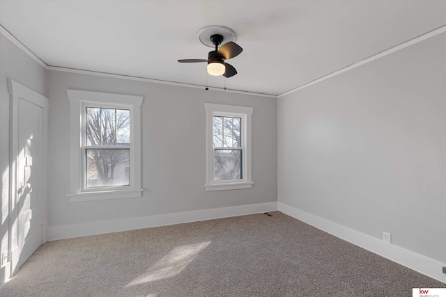 carpeted spare room featuring baseboards, ornamental molding, and a ceiling fan