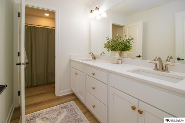 bathroom with double vanity, a sink, and wood finished floors