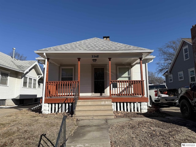 bungalow-style home with a porch and roof with shingles