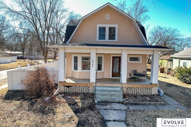 view of front of house featuring covered porch, roof with shingles, fence, and a gambrel roof