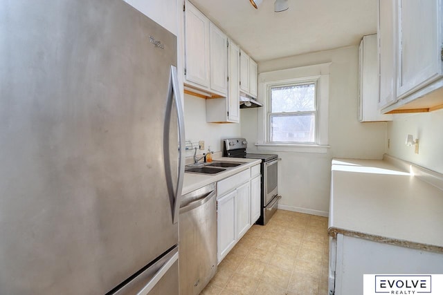 kitchen with under cabinet range hood, a sink, white cabinets, light countertops, and appliances with stainless steel finishes