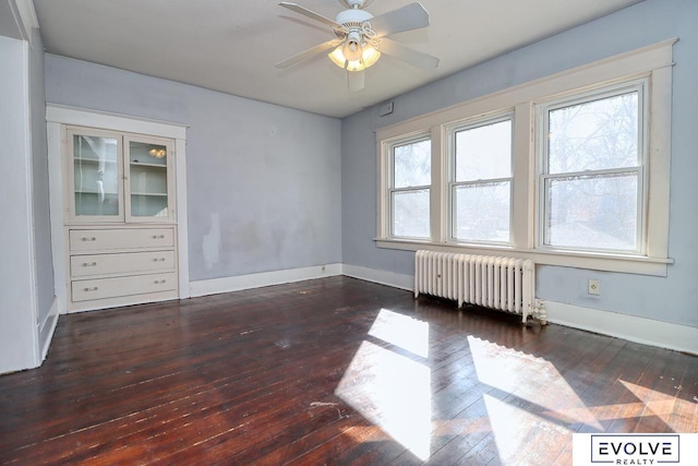 unfurnished room with baseboards, hardwood / wood-style floors, a wealth of natural light, and radiator