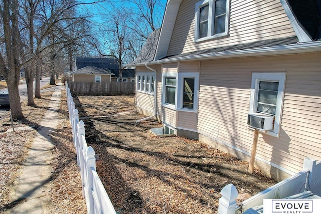 view of side of property featuring cooling unit, roof with shingles, and fence