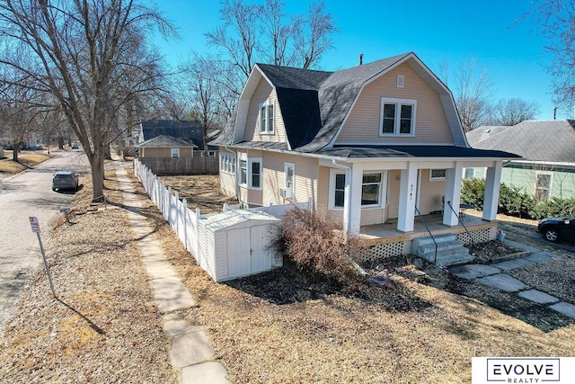 view of side of home featuring a fenced front yard, a porch, a shingled roof, and a gambrel roof