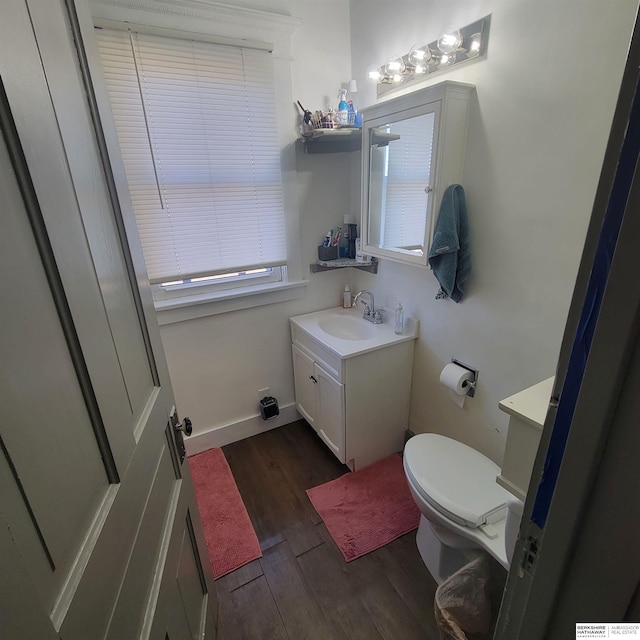 bathroom featuring baseboards, vanity, toilet, and wood finished floors