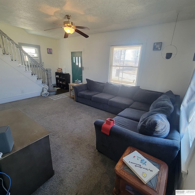 carpeted living room featuring stairs, a textured ceiling, and a ceiling fan