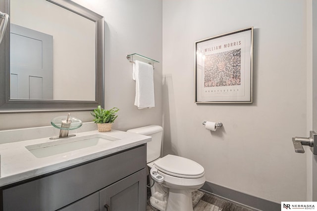 bathroom with baseboards, toilet, and vanity