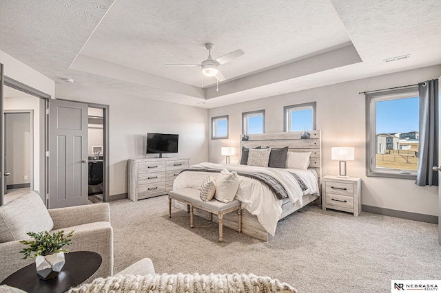 bedroom featuring baseboards, visible vents, a raised ceiling, and light carpet