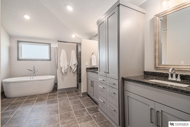 full bath with a sink, a soaking tub, two vanities, and recessed lighting