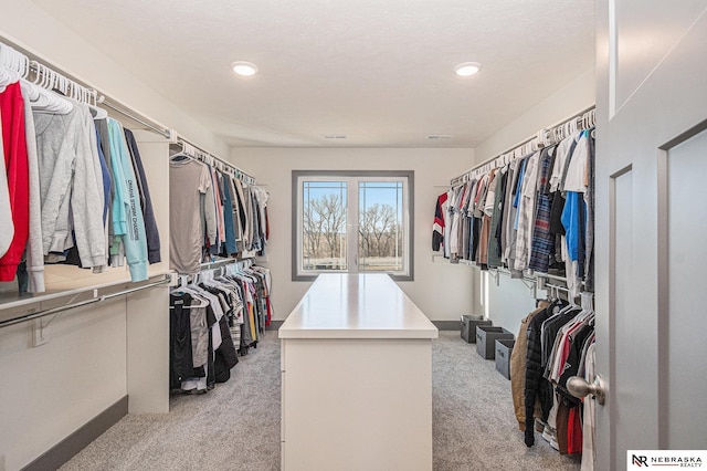 walk in closet with light carpet