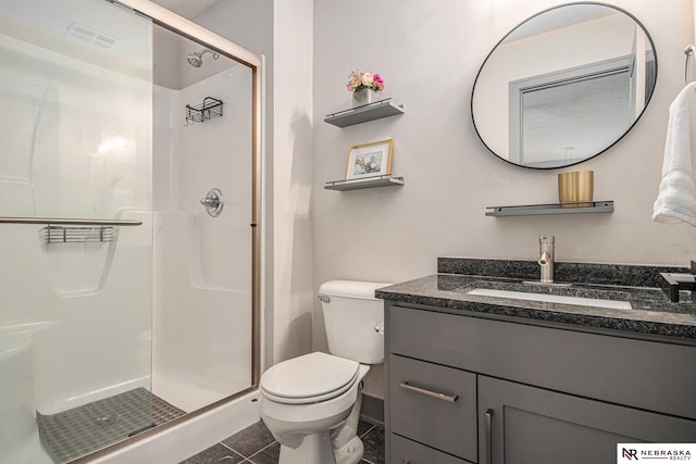 bathroom featuring vanity, tile patterned floors, toilet, and a stall shower