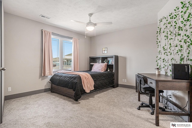 carpeted bedroom featuring a textured ceiling, baseboards, and a ceiling fan